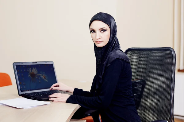 En kvinna i hijab arbetar på en dator — Stockfoto