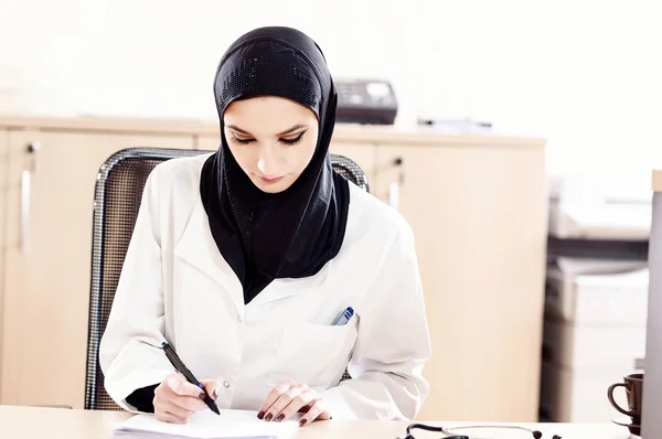 Médico musulmán femenino llena los archivos médicos — Foto de Stock