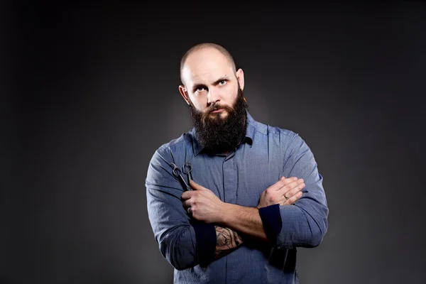 Bald man with a beard holding a pair of scissors. Hands crossed on his chest — Stock Photo, Image
