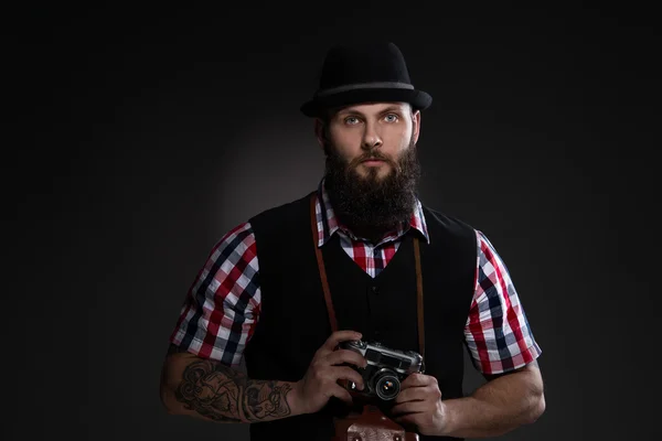 Uomo barbuto in un cappello che tiene una vecchia macchina fotografica — Foto Stock