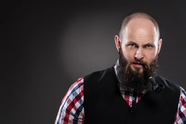 Bearded man in a checkered shirt smoking a pipe — Stock Photo, Image