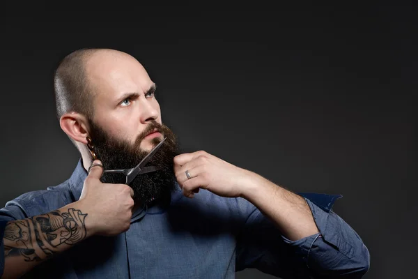 Hombre cortando barba contra un fondo gris —  Fotos de Stock