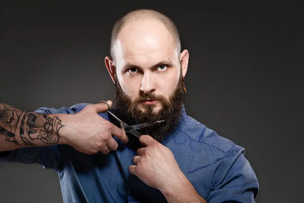 Portrait of a bearded man grooming his beard with scissors — Stock Photo, Image