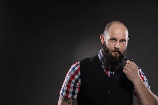 Мускулистый татуированный мужчина курит трубку — стоковое фото