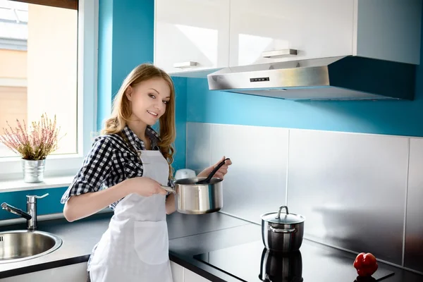 Krásná světlovlasá žena vaření v moderní kuchyni. — Stock fotografie