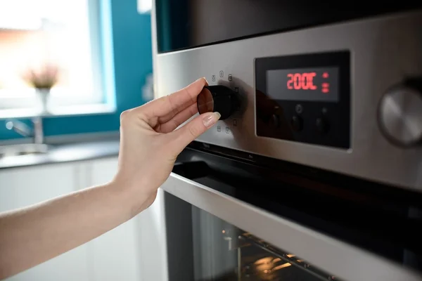 Primo piano del controllo della temperatura della mano della donna sul forno — Foto Stock