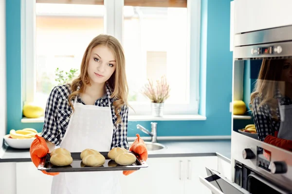 Hausfrau hält heiße Bratpfanne mit frisch gebackenen Semmeln. — Stockfoto