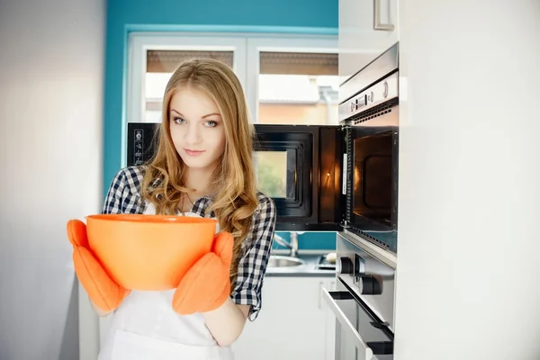 Beautiful housewife holding a hot bowl — Stock Photo, Image