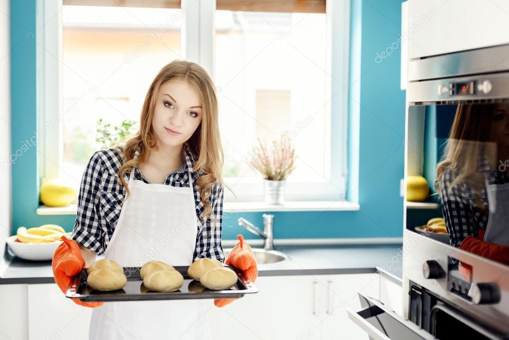 housewife holding hot roasting pan with  freshly baked bread rolls.