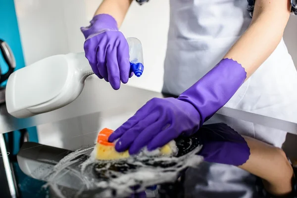 Las manos de la mujer limpiando la tapa de la cocina en guantes —  Fotos de Stock