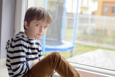 Küçük çocuk oturan bir pencere önünde oturan