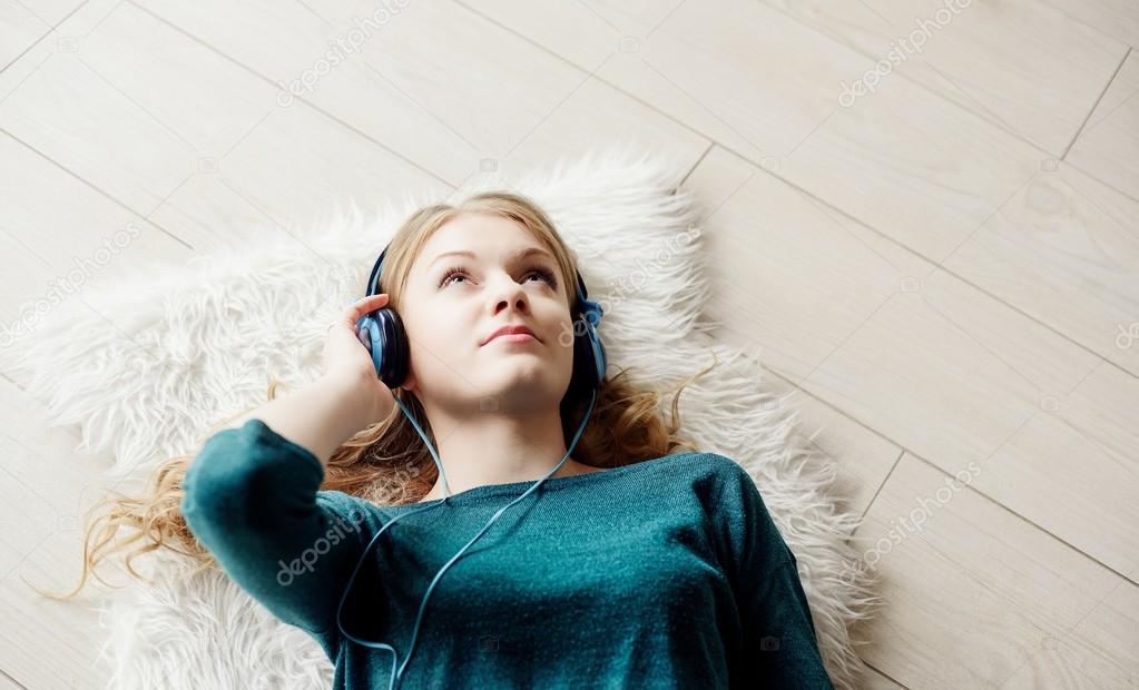 Beautiful blond woman listening to music through headphones