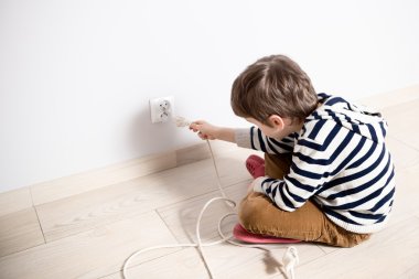 Elektrik fişi ile oynamaya meraklı küçük çocuk.