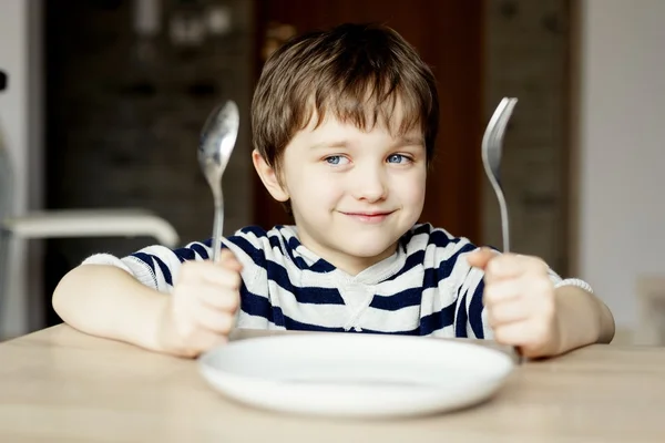 Szczęśliwy chłopiec czeka na obiad. — Zdjęcie stockowe