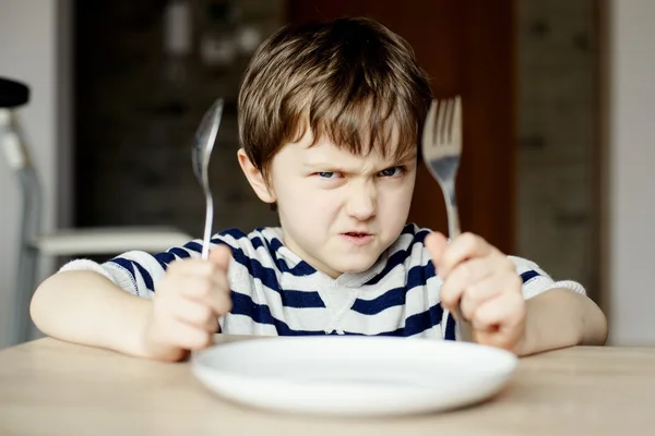 Dühös kisfiú vár vacsorára Stock Fotó