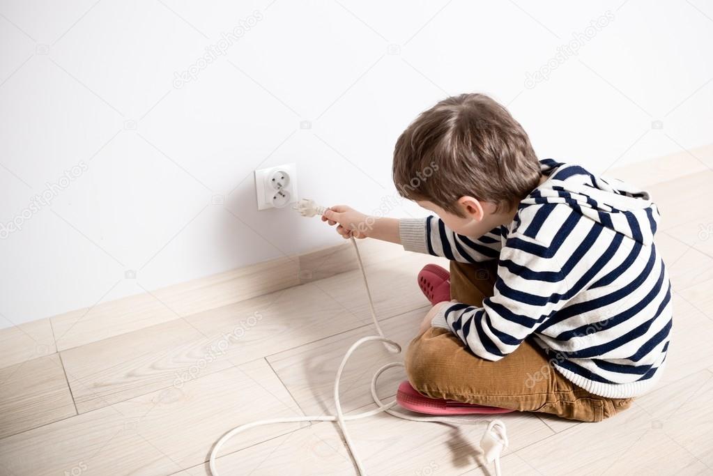 Curious little boy playing with electric plug.