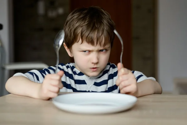Zdenerwowany mały chłopiec czeka na obiad — Zdjęcie stockowe