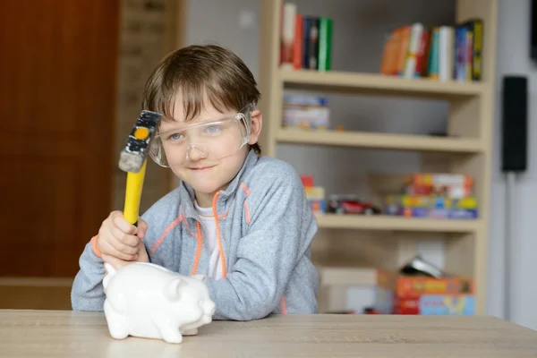 Junge zertrümmert Sparschwein mit Hammer — Stockfoto