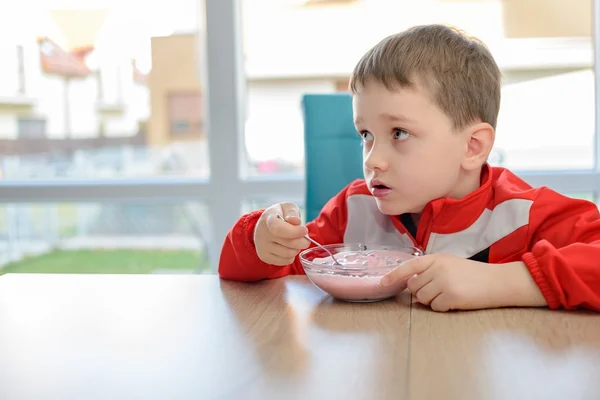 O menino comendo iogurte de frutas em uma tigela — Fotografia de Stock