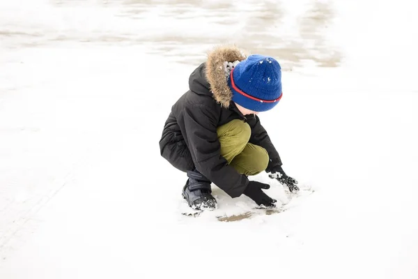 Jongetje spelen in de tuin met sneeuw — Stockfoto