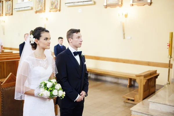 A noiva e o noivo de pé no altar da igreja — Fotografia de Stock