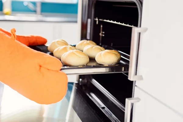 Primer plano de las manos del panadero sacando rollos calientes del horno . — Foto de Stock