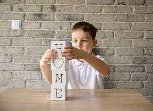 Menino jogando tijolos de madeira com letras fazendo palavra casa — Fotografia de Stock