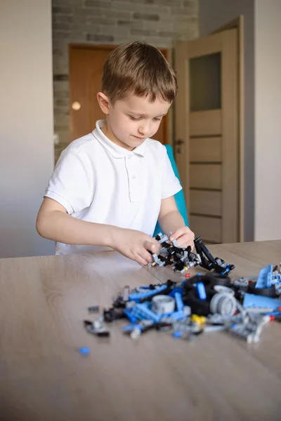 Enfant jouant avec des blocs de plastique techniques à l'intérieur . — Photo