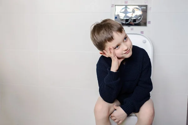6-jarige jongen denken zittend op het toilet. — Stockfoto