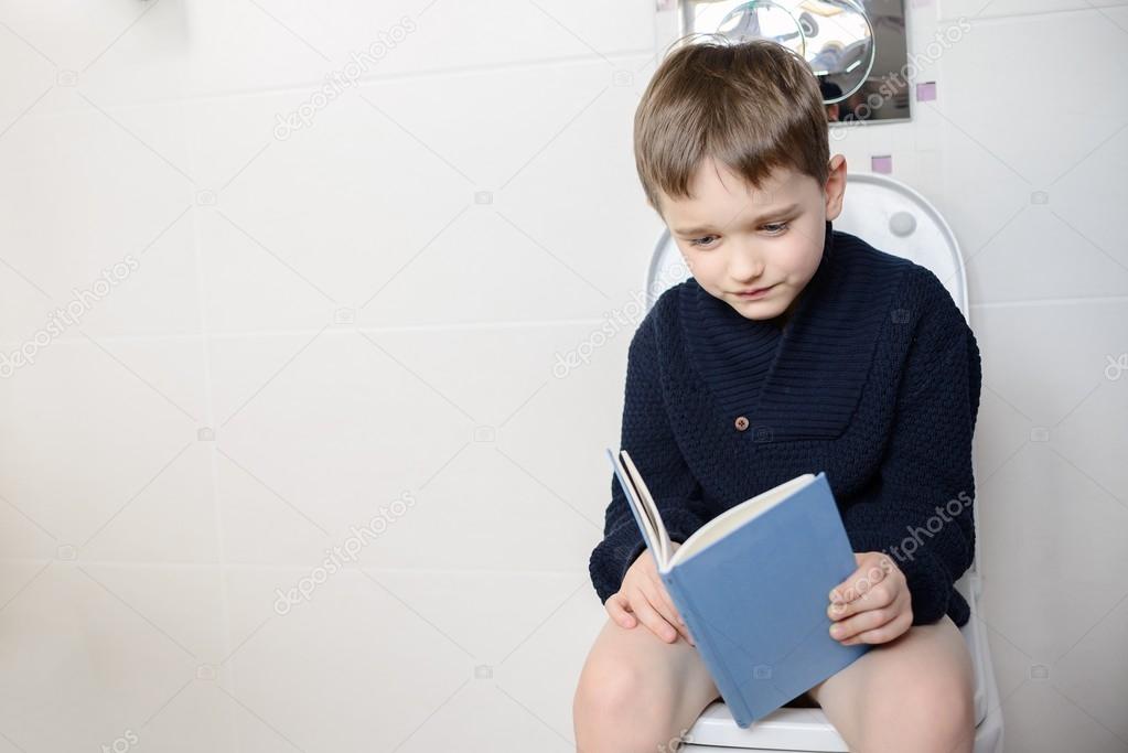 Child sitting on the toilet and reading a  book