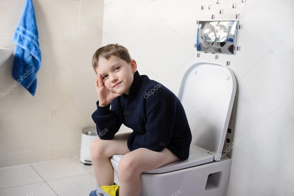 Thoughtful  boy sitting on the toilet.