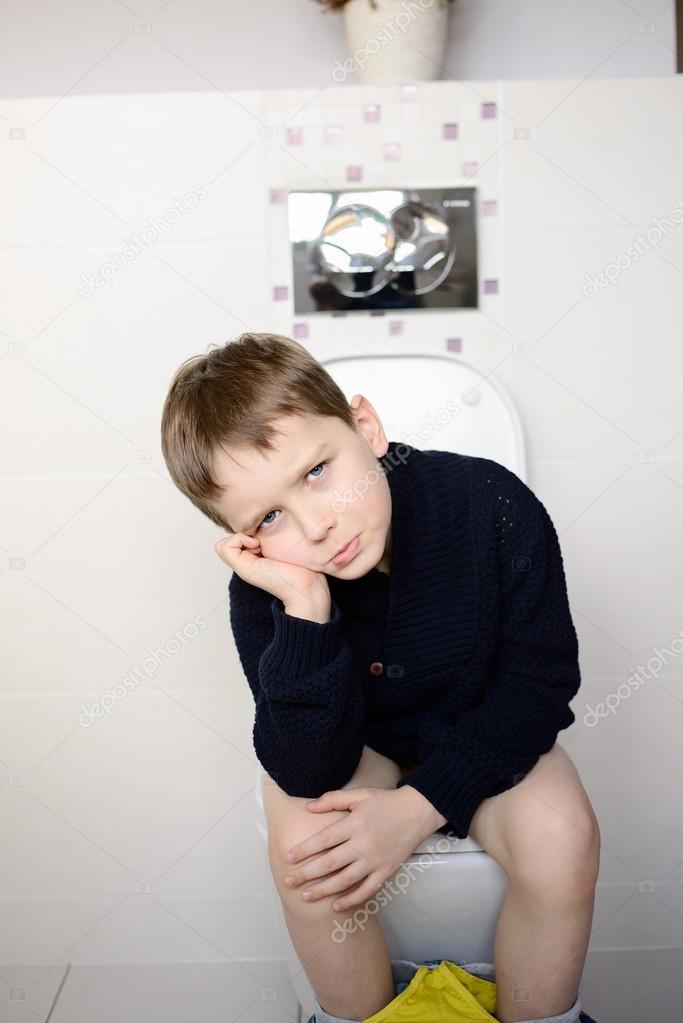 Offended boy sitting on the toilet. 