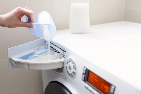 Closeup on woman's hand pouring detergent into the washing machine — Stock Photo, Image