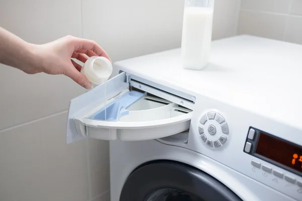 Fechar a mão de uma mulher derramando amaciador de tecido líquido branco — Fotografia de Stock