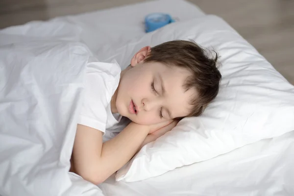 Ребенок спит в кровати, счастливо ложится спать в белой спальне — стоковое фото