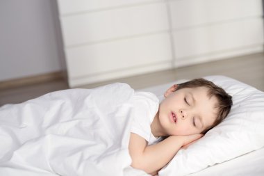 Yatakta uyuyan küçük çocuk mutlu yatmadan beyaz yatak odasında