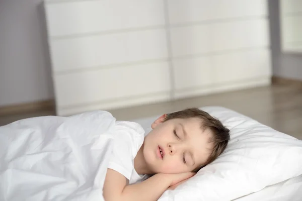 Pojken sover i sängen, glad läggdags i vita sovrum — Stockfoto