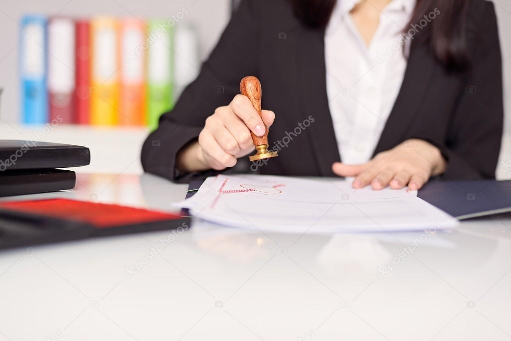 Close up on woman's notary public hand stamping the document