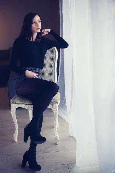 Jonge aantrekkelijke brunette vrouw zittend op de stoel van de ouderwetse — Stockfoto