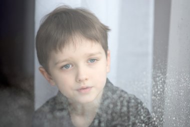 Depresyonda çocuk pencereden dışarı bakarak.