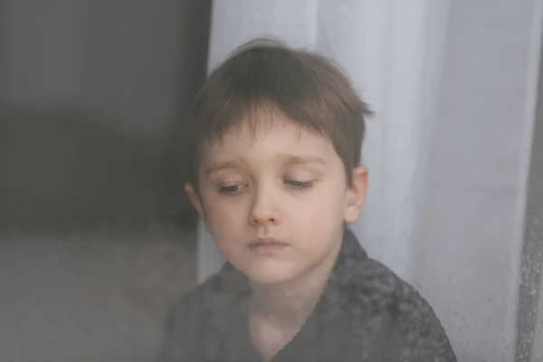 7 ans garçon enfant regardant par la fenêtre — Photo