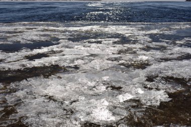 Nehir kenarındaki güneş ışığında ince buz parçaları, ilkbahar öncesi kavramı.