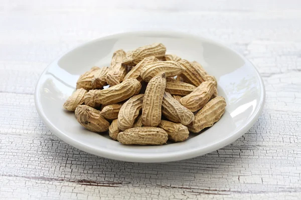 Cacahuetes negros en plato blanco — Foto de Stock