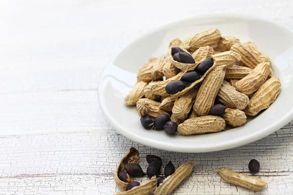 Cacahuetes negros en plato blanco — Foto de Stock