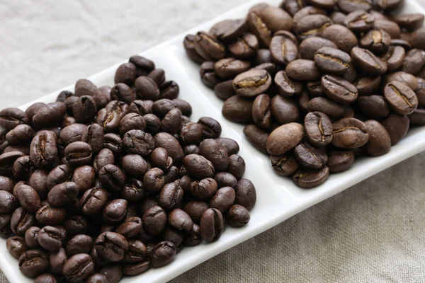 Grãos de café torrados, peaberry e feijão liso — Fotografia de Stock