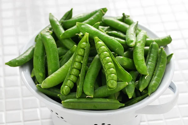 エナメル質のザルに新鮮に選んだ緑のエンドウ豆の鞘 — ストック写真