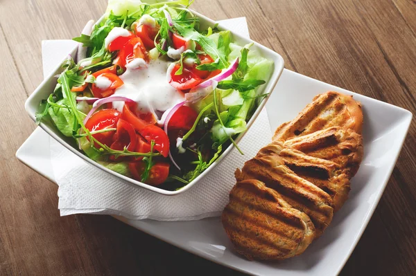 Frischer Salat mit Tomaten und Soße und Brot — Stockfoto