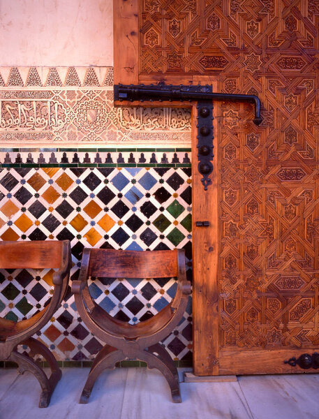 пустые стулья во дворце Альгамбра и мавританская плитка позади; Альгамбра является объектом всемирного наследия ЮНЕСКО в Гранаде, Андалусии, Испании