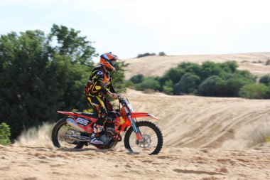 Motosikletçi kum tepeciğinin üzerinden uçar