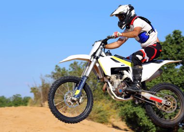 Motosikletçi kum tepeciğinin üzerinden uçar